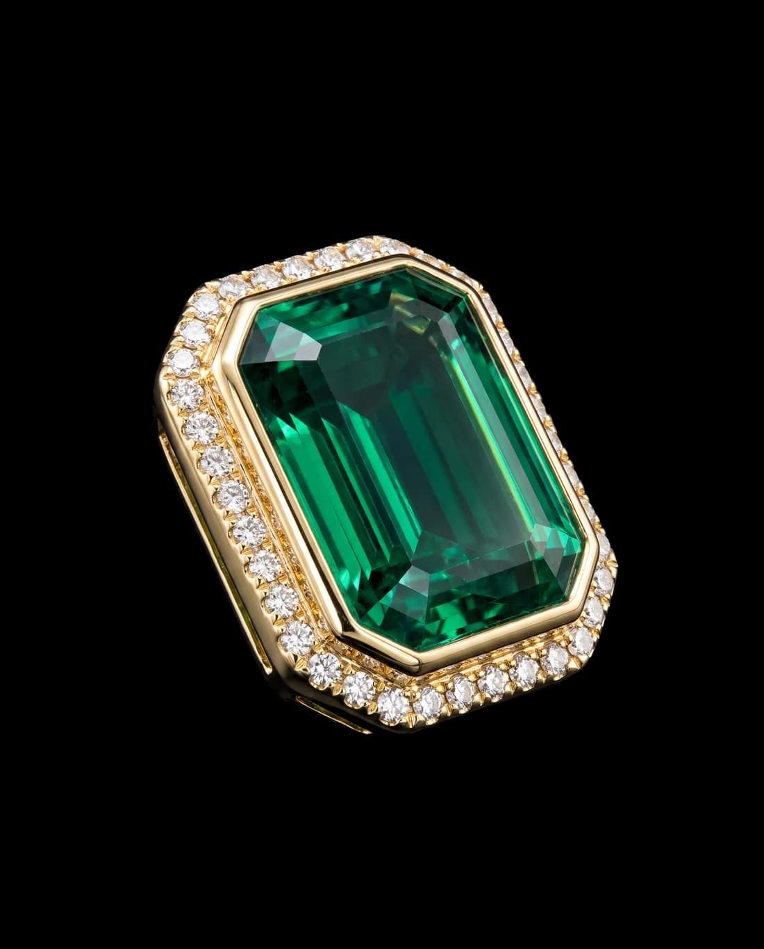 An emerald set in a gold bezel ringed with diamonds